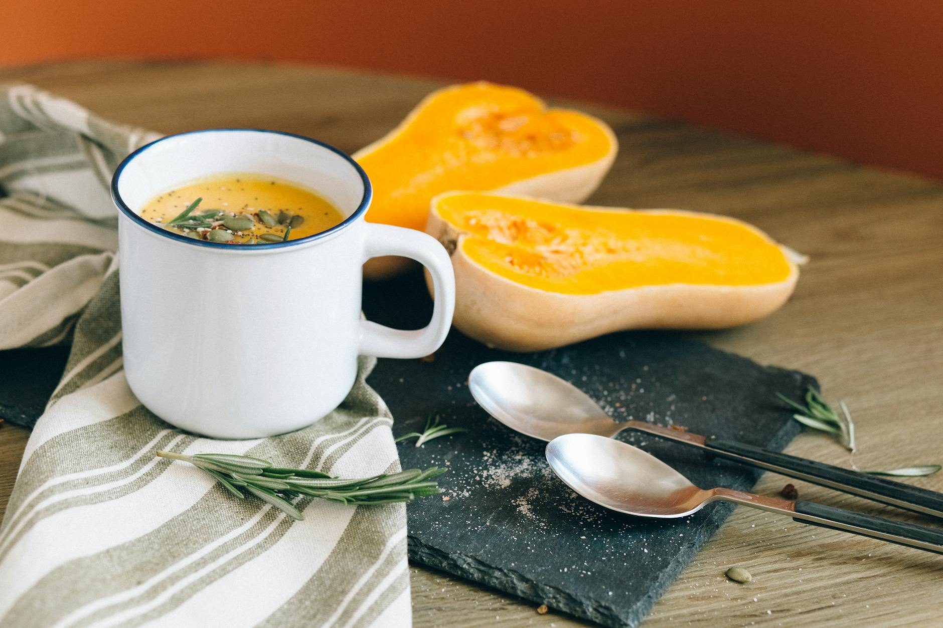 white ceramic mug near stainless steel spoon