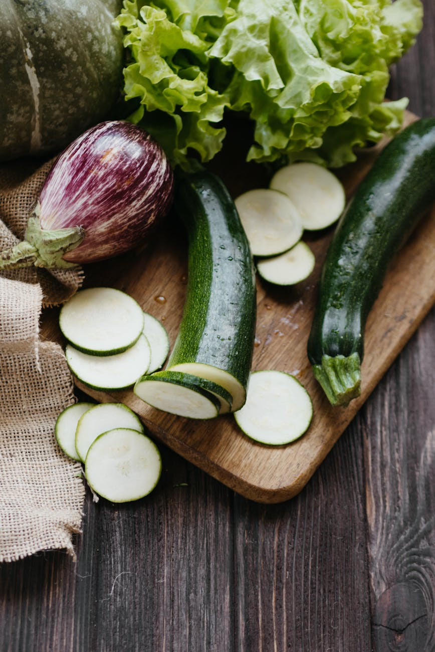 sliced zucchini eggplant and lettuce on a wooden chopping board